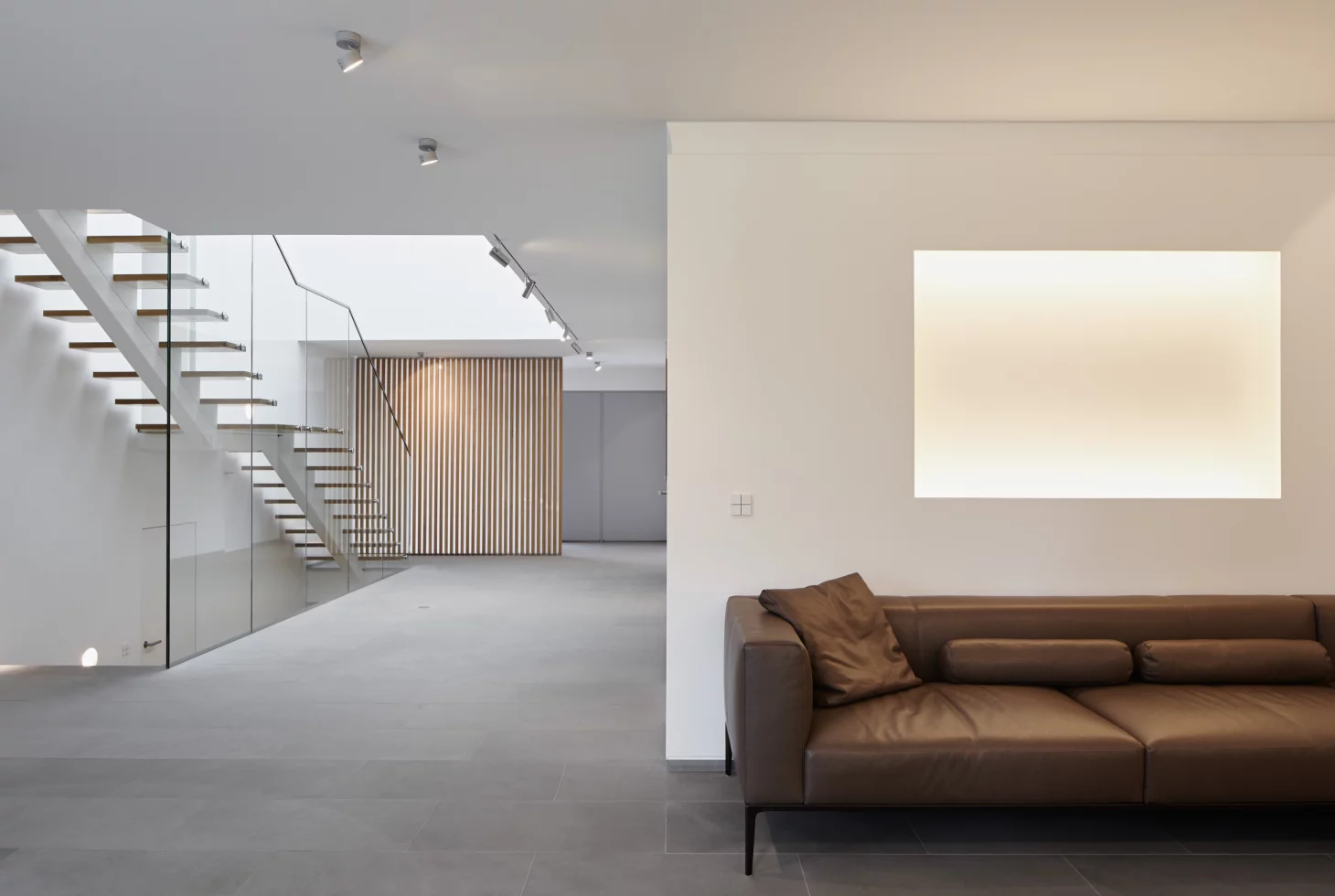 Übergang zwischen Wohnraum und Galeriebreich mit Natursteinboden und rückseitigem Blick auf die Treppe