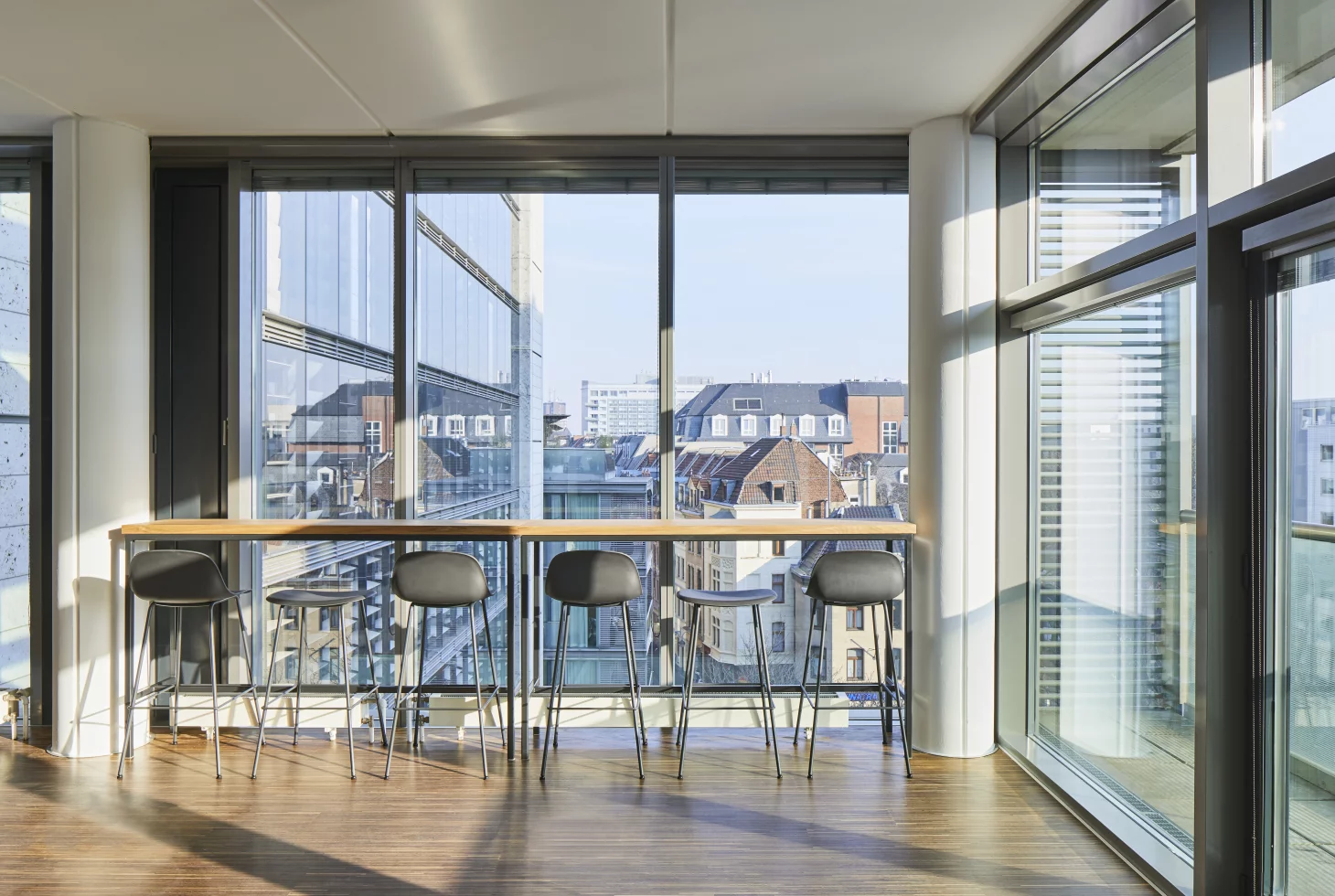 Loungebereich mit Tresen vor raumhoher Fensteröffnung mit Blick über Köln