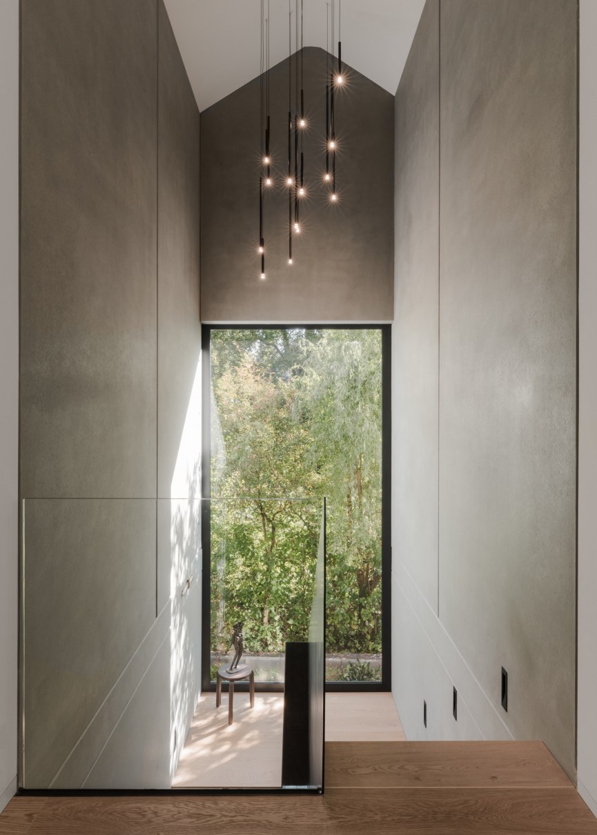 Gläserner Fassadenausschnitt mit Einblicken in den Wohnbereich und einem Wasserband im Außenbereich