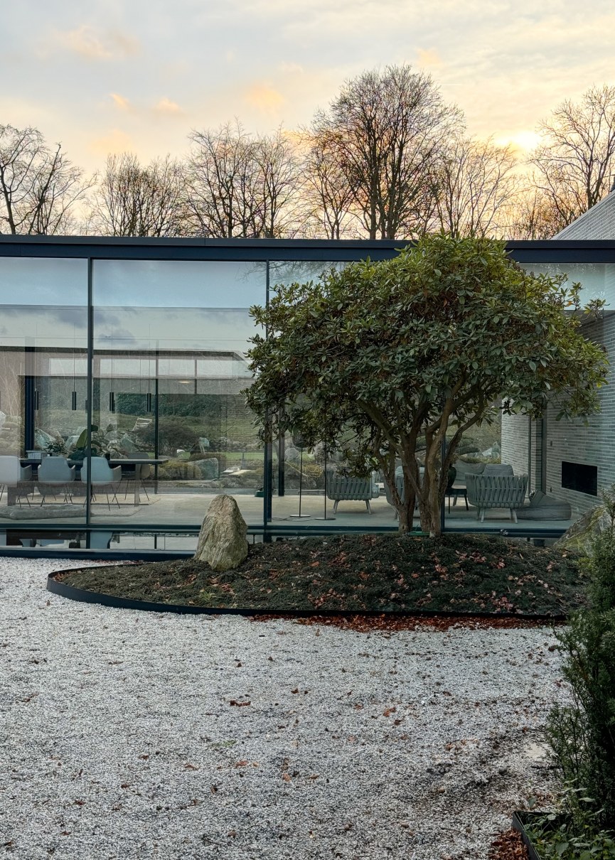 Blick auf verputzten Baukörper, der an Glasfläche grenzt mit Einsichten in das luxuriöse Badezimmer